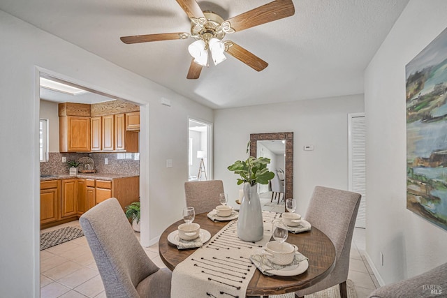 dining space featuring light tile patterned floors, a ceiling fan, and baseboards