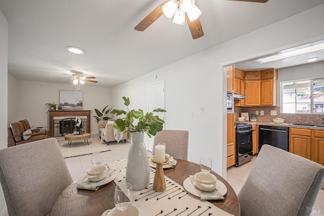 dining room featuring light tile patterned floors, a fireplace, and a ceiling fan