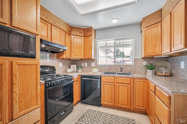 kitchen featuring tasteful backsplash, under cabinet range hood, light tile patterned floors, black appliances, and a sink