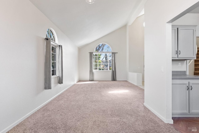 empty room with baseboards, carpet, and vaulted ceiling