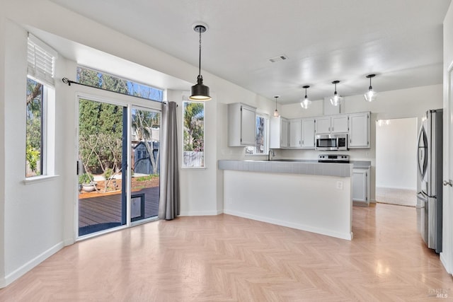 kitchen featuring a peninsula, a healthy amount of sunlight, visible vents, and appliances with stainless steel finishes