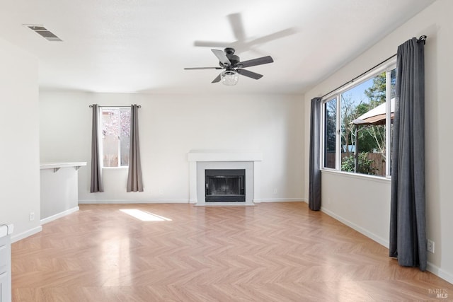 unfurnished living room featuring visible vents, a fireplace with flush hearth, baseboards, and a ceiling fan