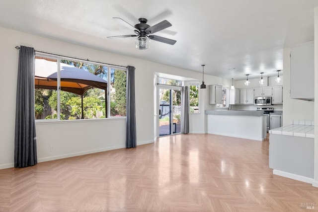 unfurnished living room with baseboards and ceiling fan