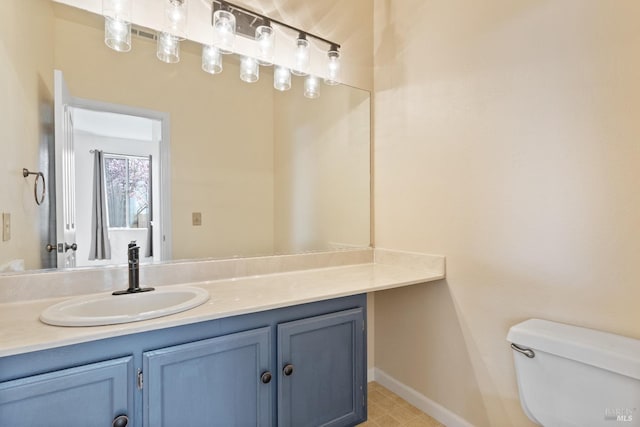 half bath with toilet, vanity, and baseboards