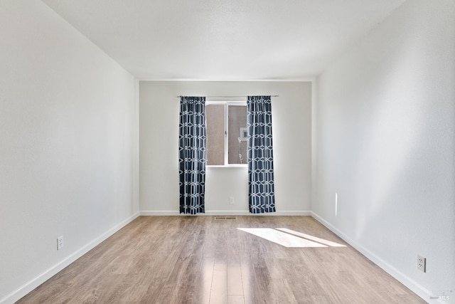 empty room with visible vents, wood finished floors, and baseboards