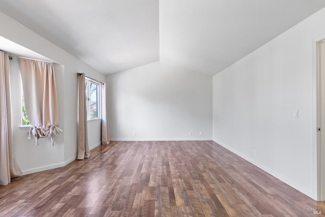 spare room featuring baseboards, lofted ceiling, and wood finished floors