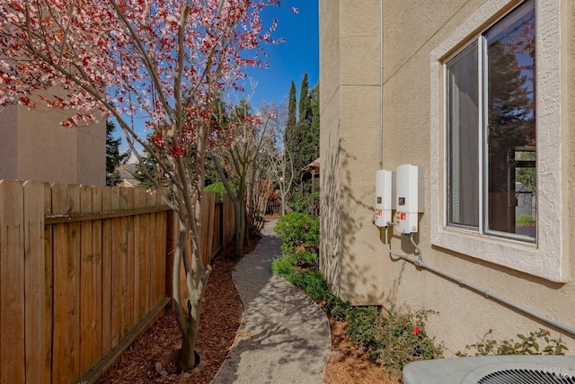 view of side of property with stucco siding, cooling unit, and fence