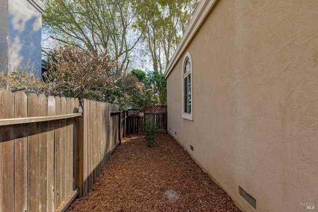 view of side of home with stucco siding and fence