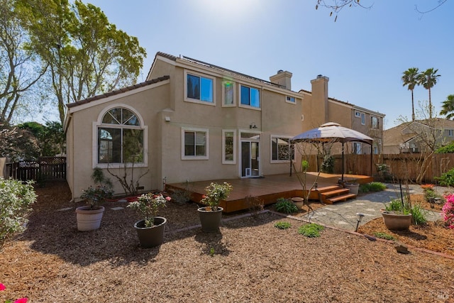 back of property featuring a deck, a fenced backyard, a chimney, and stucco siding