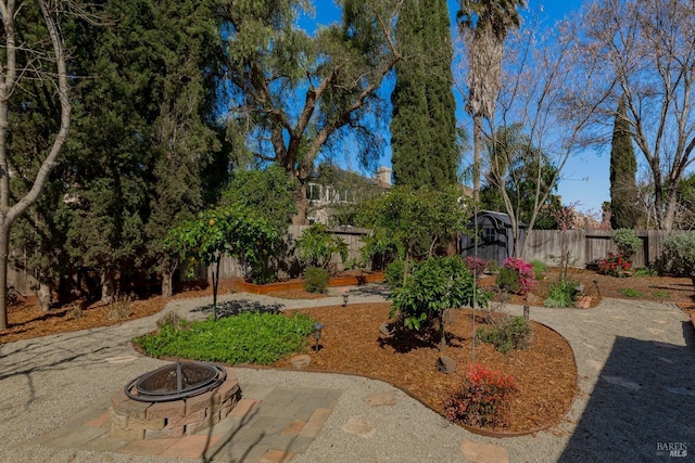 view of yard featuring a patio, fence, and a fire pit