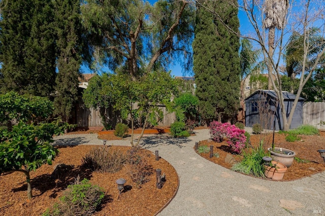 view of yard featuring a storage shed, a fenced backyard, and an outdoor structure