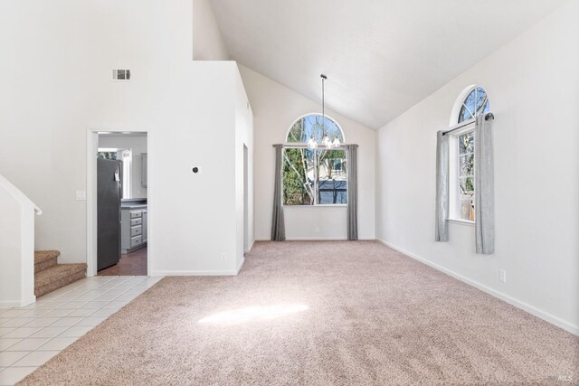 unfurnished room with a chandelier, light colored carpet, high vaulted ceiling, and stairs