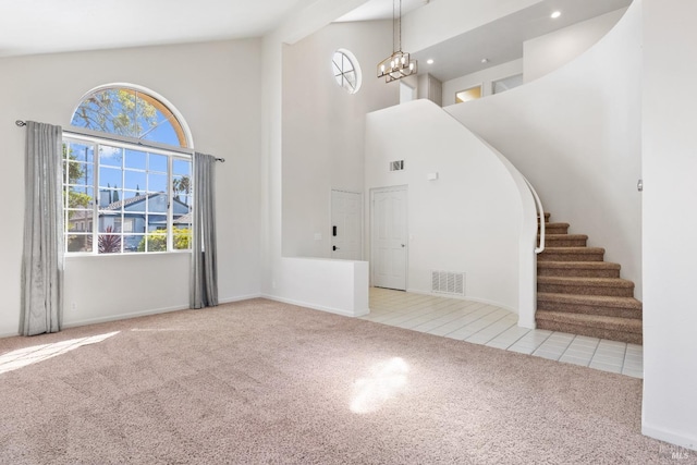 carpeted entrance foyer with tile patterned flooring, visible vents, a chandelier, stairs, and high vaulted ceiling