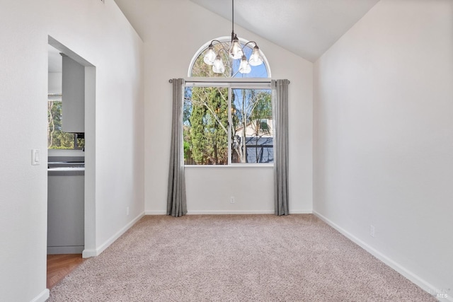 spare room with baseboards, lofted ceiling, carpet floors, and an inviting chandelier