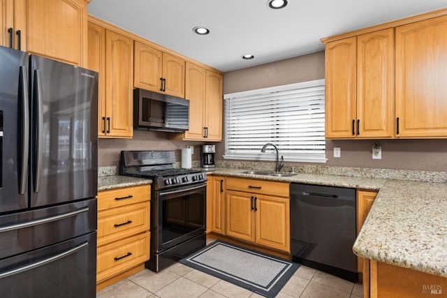 kitchen with a sink, light stone counters, light tile patterned floors, and stainless steel appliances