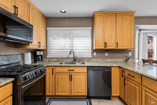 kitchen with stainless steel gas range oven, light stone countertops, black dishwasher, light tile patterned floors, and a sink