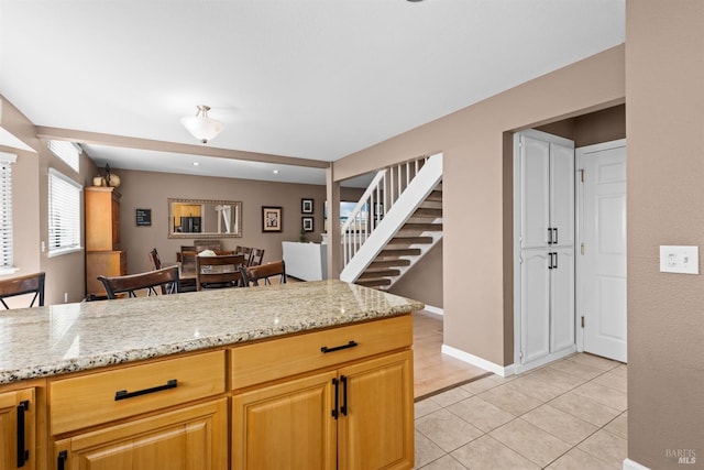 kitchen with light tile patterned floors, light stone countertops, and baseboards