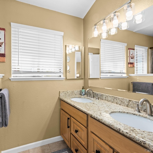 full bath with a sink, baseboards, double vanity, and tile patterned floors