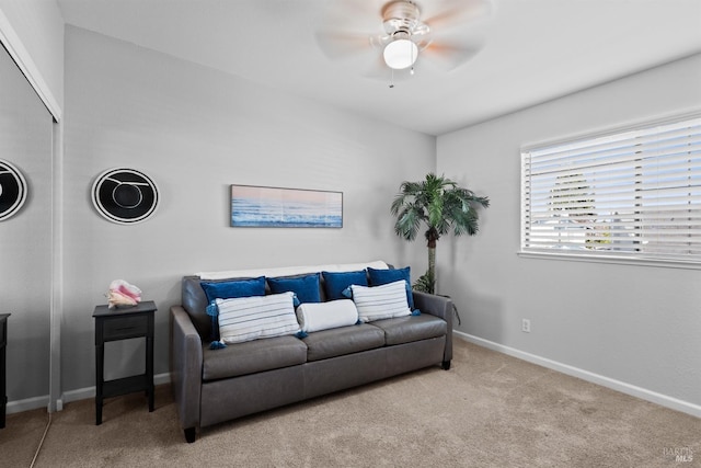 carpeted living room featuring baseboards and ceiling fan