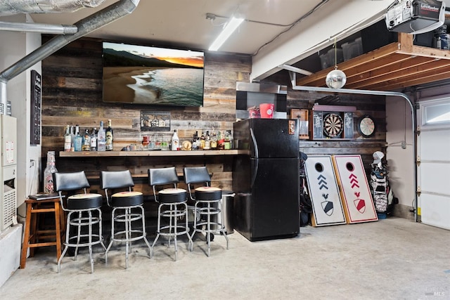 bar featuring wood walls, a dry bar, and freestanding refrigerator