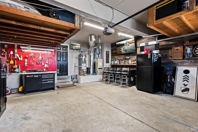 interior space featuring strapped water heater, a workshop area, a garage door opener, and freestanding refrigerator