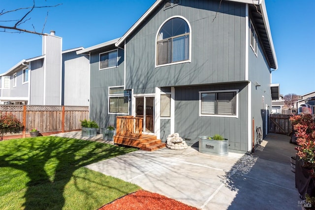 rear view of house with a gate, fence, a yard, a chimney, and a patio area