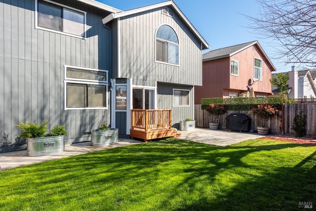 rear view of house featuring a lawn, a patio, and fence