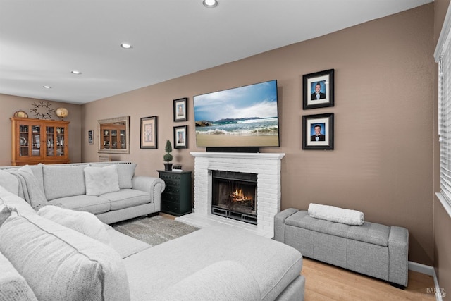 living area with recessed lighting, baseboards, a fireplace, and light wood finished floors