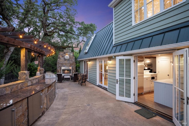 view of patio with an outdoor stone fireplace, an outdoor kitchen, and a pergola