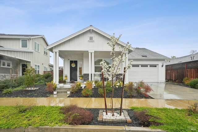 view of front facade featuring a porch, fence, board and batten siding, concrete driveway, and a garage