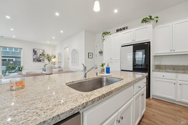 kitchen featuring a sink, recessed lighting, white cabinets, light wood finished floors, and light stone countertops