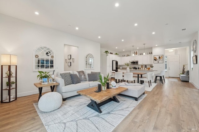 living room with recessed lighting, baseboards, and light wood finished floors