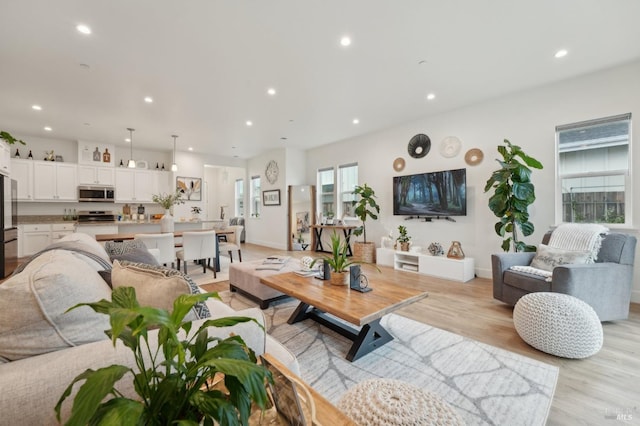 living area featuring recessed lighting, baseboards, and light wood finished floors