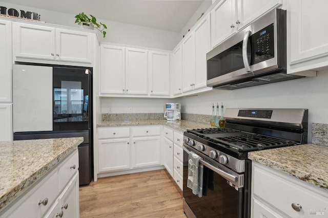 kitchen featuring white cabinets, light stone counters, light wood-type flooring, and appliances with stainless steel finishes