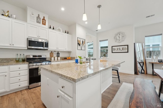 kitchen featuring white cabinetry, light wood-style flooring, a kitchen island with sink, and stainless steel appliances