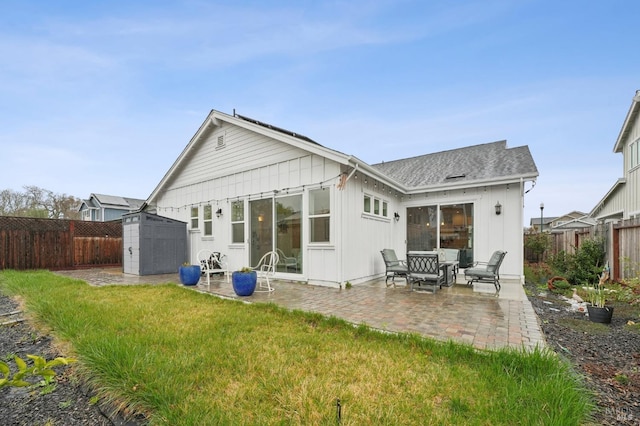 back of house featuring an outbuilding, a fenced backyard, a shed, and a patio