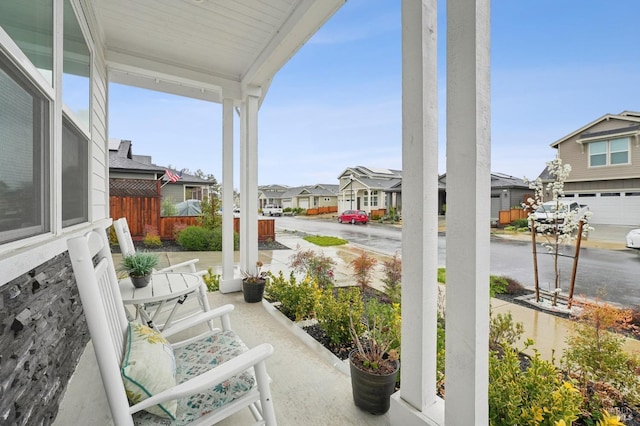 view of patio featuring a residential view, covered porch, and fence