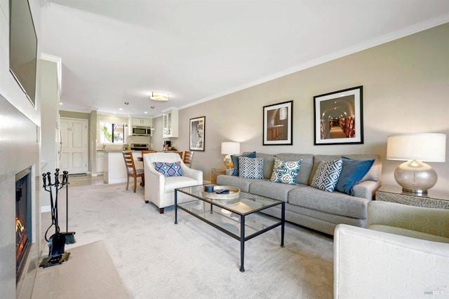 living room with crown molding, light colored carpet, and a warm lit fireplace