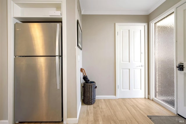 hallway featuring light wood-type flooring, crown molding, and baseboards