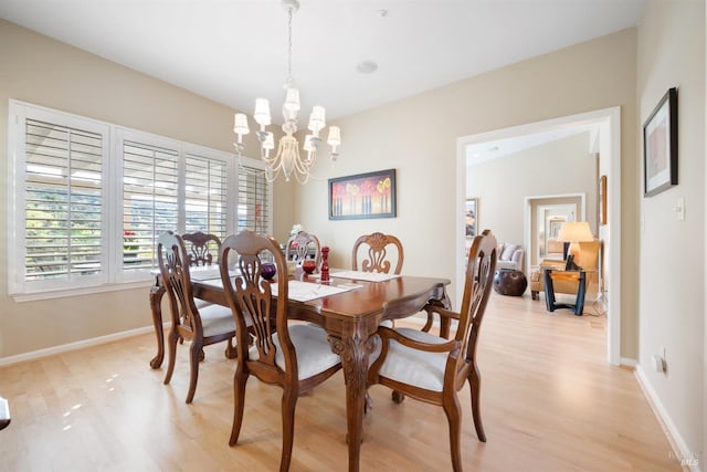 dining room with a chandelier, baseboards, and light wood-style floors