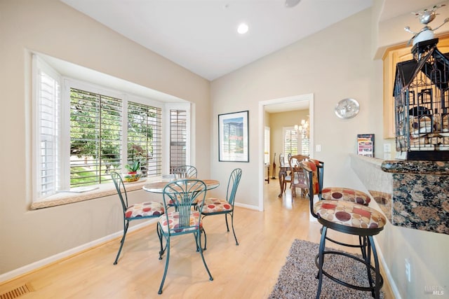 dining room with lofted ceiling, light wood-style flooring, baseboards, and visible vents