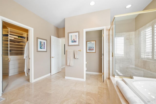 full bathroom featuring a spacious closet, baseboards, toilet, a garden tub, and tiled shower