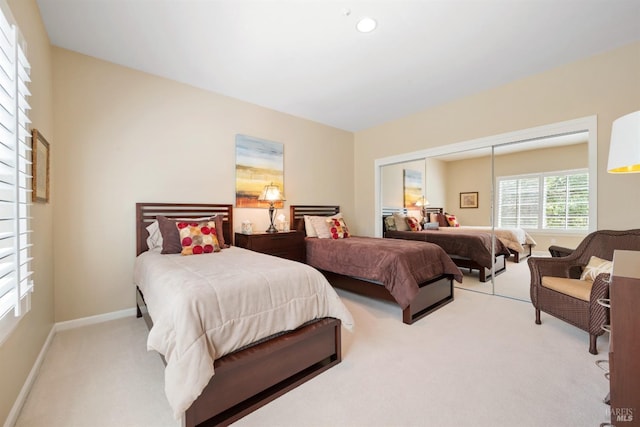 bedroom featuring recessed lighting, light colored carpet, baseboards, and a closet