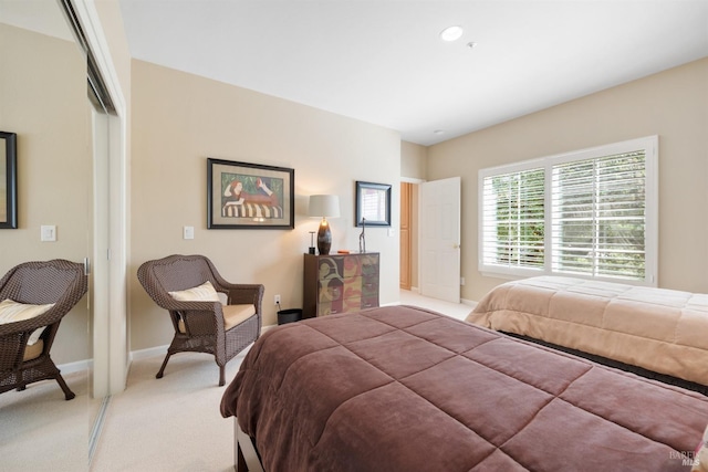 bedroom with baseboards, a closet, and light carpet