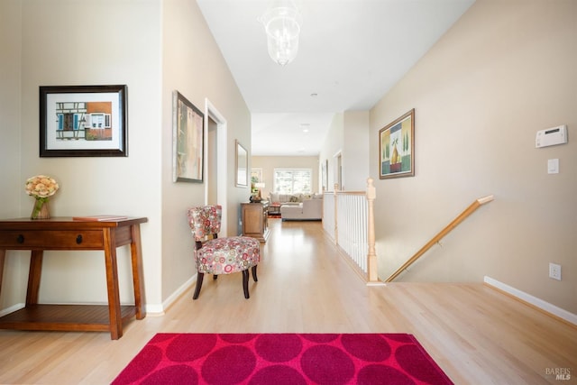 hallway featuring an upstairs landing, baseboards, and wood finished floors