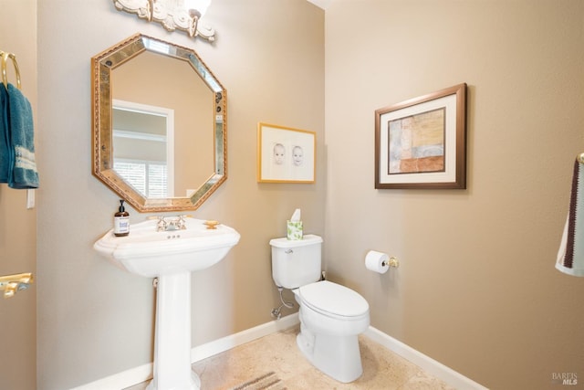 half bathroom with tile patterned floors, toilet, baseboards, and a sink