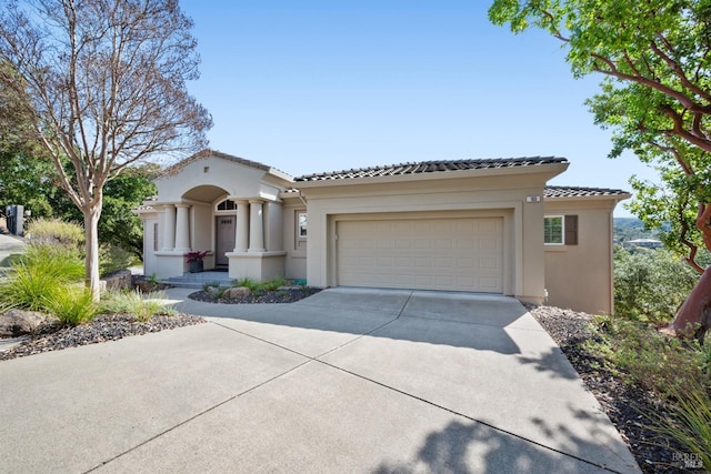 mediterranean / spanish-style house with concrete driveway, a tiled roof, a garage, and stucco siding