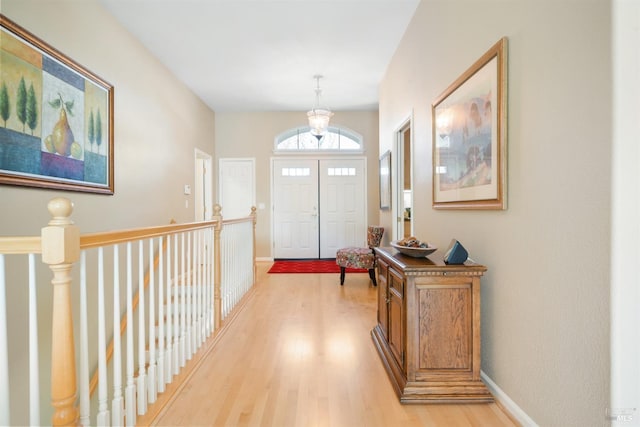 entryway featuring light wood-style flooring, a notable chandelier, and baseboards