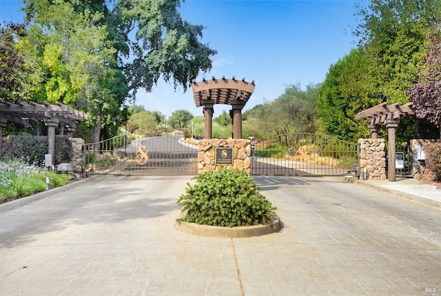 view of road with a gated entry, curbs, and a gate