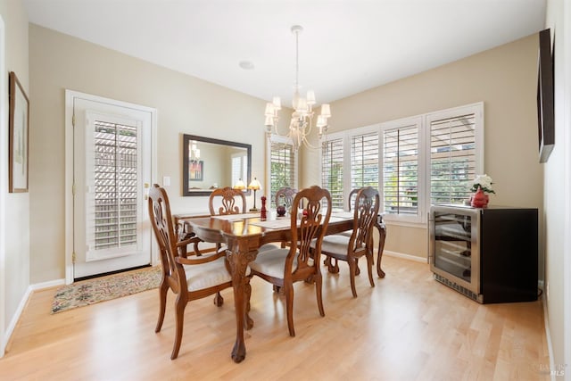 dining area with wine cooler, baseboards, light wood finished floors, and a chandelier